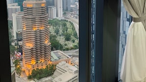 Une chambre d’hôtel située dans un immeuble de grande hauteur, offrant une vue sur le paysage urbain, notamment sur un bâtiment remarquable dont les fenêtres sont illuminées.