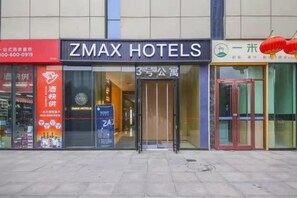 Ein Hotel Eingang mit einem gut sichtbaren Schild für ZMAX HOTELS, einer Glastür und einer roten Laternen-Dekoration.