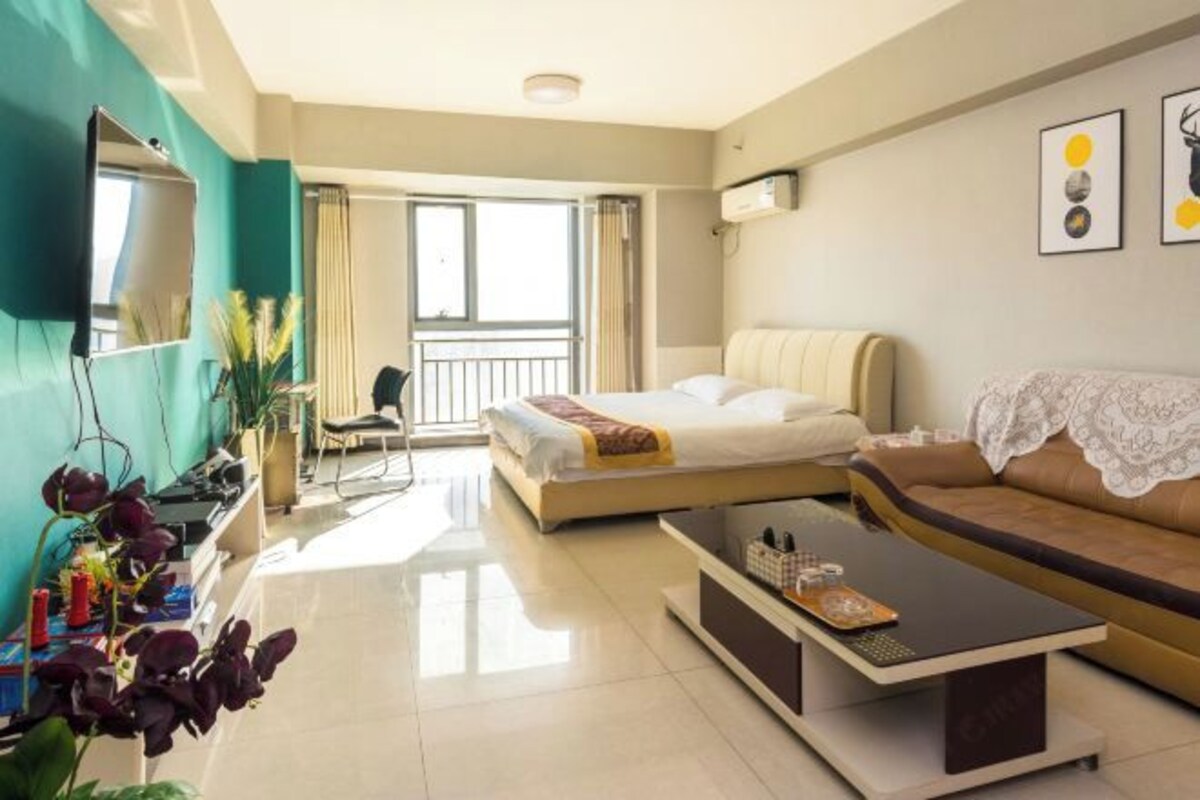 Een hotelkamer met een bed, een bank, een salontafel, een televisie en een balkon.