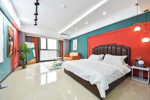 Een moderne hotelkamer met een groot bed, een zithoek met een bank en een tafel, en een balkon met uitzicht.