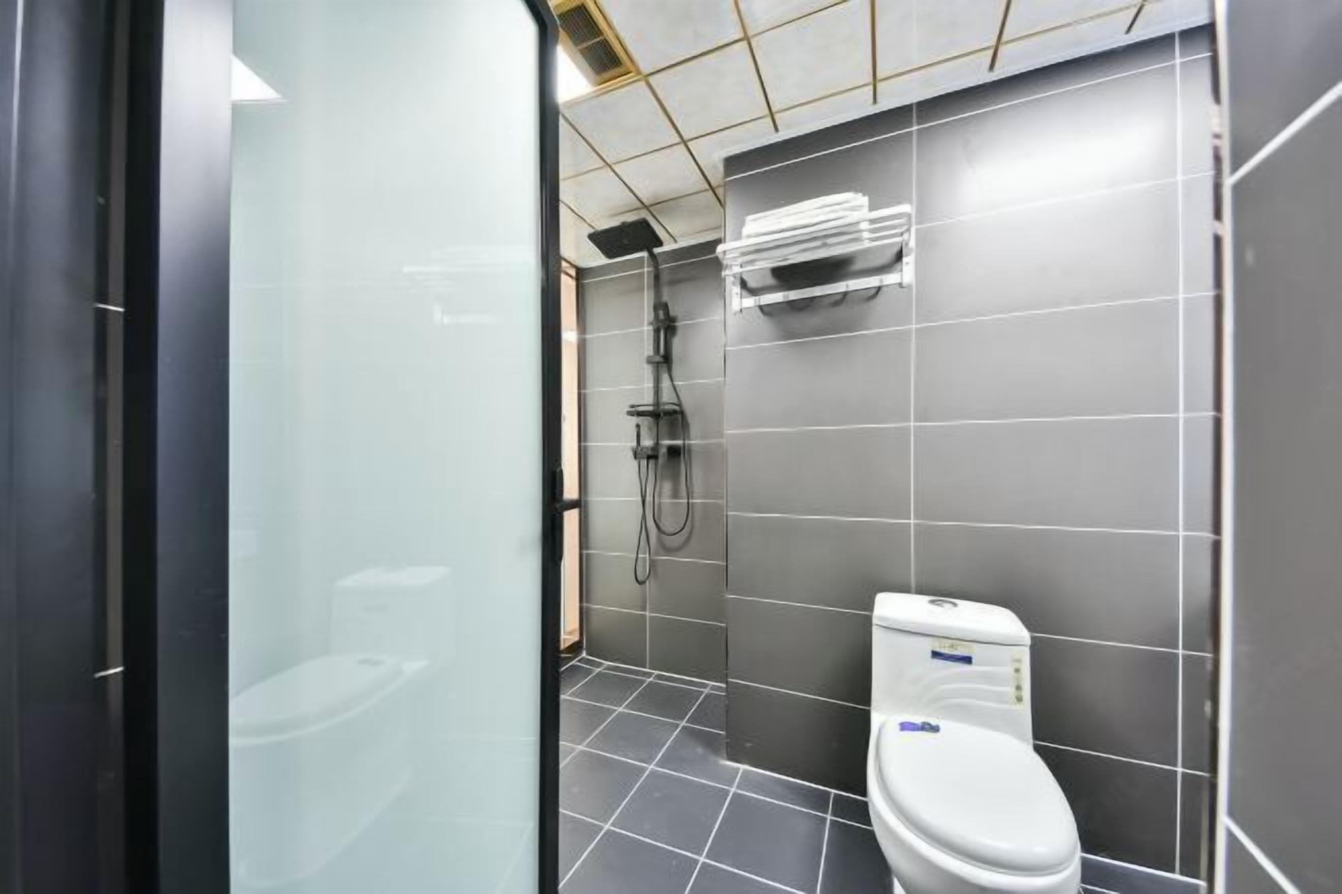A modern bathroom with a toilet, a shower, and a towel rack.