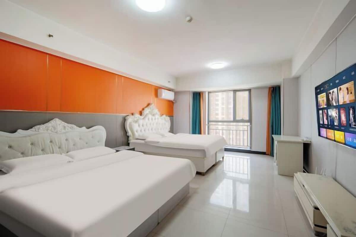 A hotel room with two beds, a large window, and a wall-mounted TV.