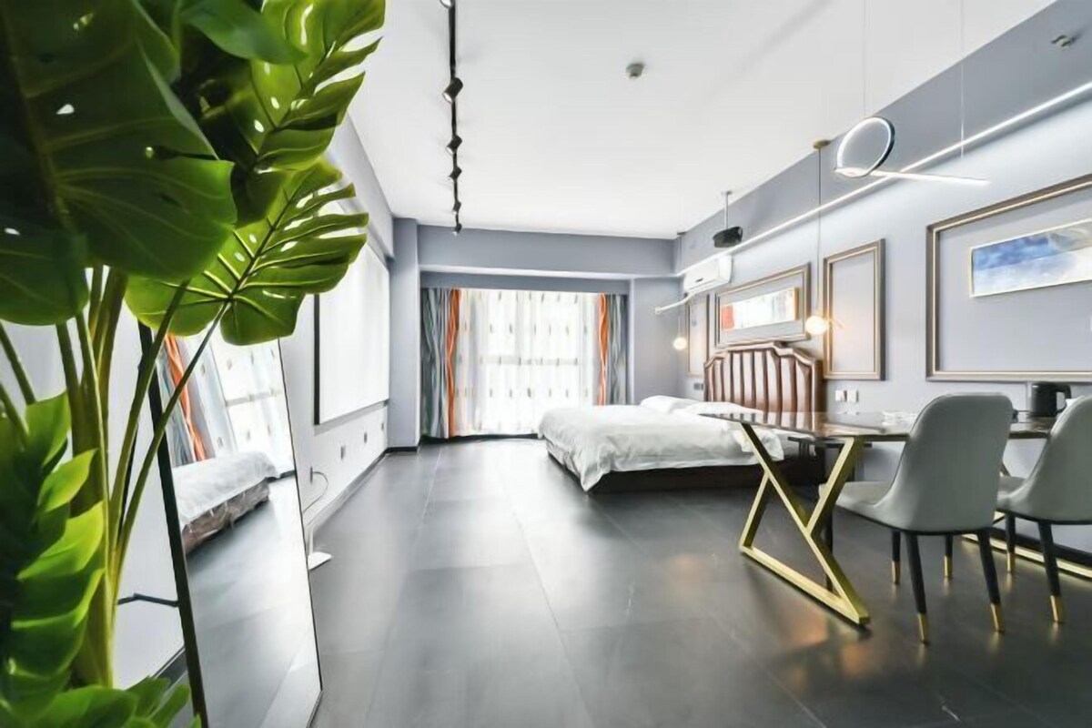 Une chambre d’hôtel moderne équipée d’un lit, d’un bureau, de chaises et d’une grande fenêtre.