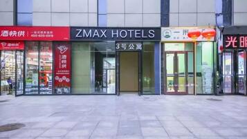 Un hotel con un letrero llamativo para ZMAX HOTELS, una fachada con un letrero rojo y un edificio con vidrio.