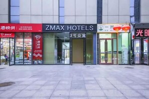 Un hotel con un letrero llamativo para ZMAX HOTELS, una fachada con un letrero rojo y un edificio con vidrio.