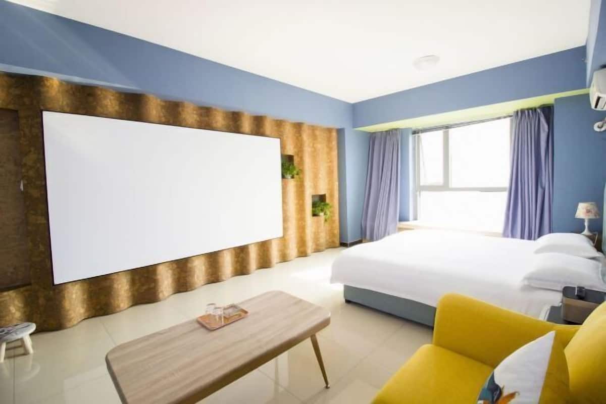 A hotel room with a bed, a desk, a chair, a TV, and a window.