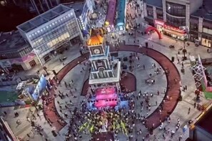 Vista aèria d'una plaça amb una estructura central, envoltada d'edificis i gent.