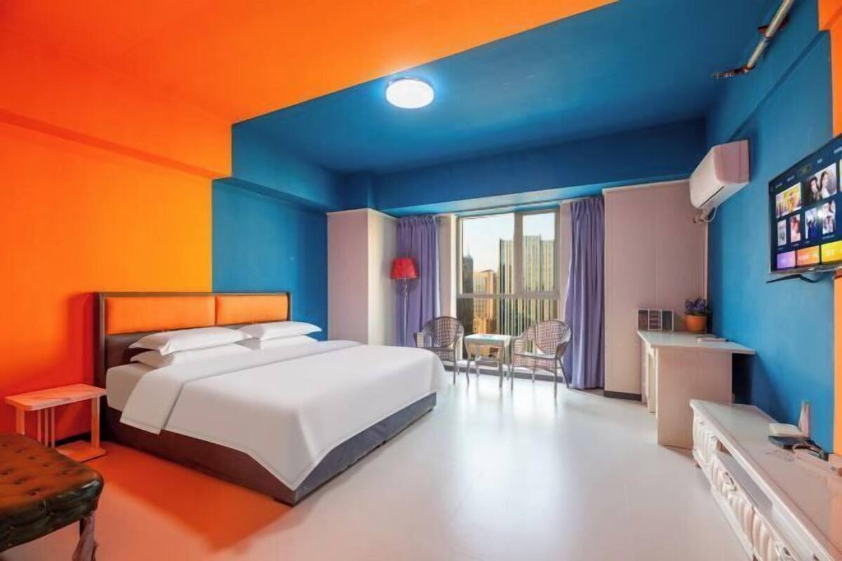 A hotel room with a bed, a desk, a chair, and a window with curtains.