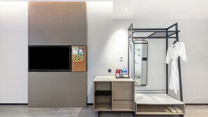 A modern hotel room with a flat-screen TV, a wooden console, a mirror, and a metal rack with a white robe. - Wanda Moments Neo Nanchang West Railway (Nanchang)