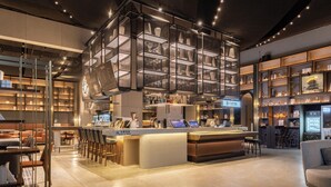Eine moderne Bar mit einer zentralen Theke, Barhocker und Regalen für Flaschen und Gläser.