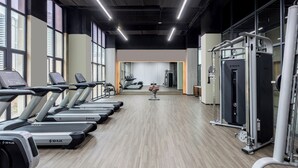 Ein Fitnessstudio mit Laufbändern, Kraftgeräten und einer Spiegelwand.
