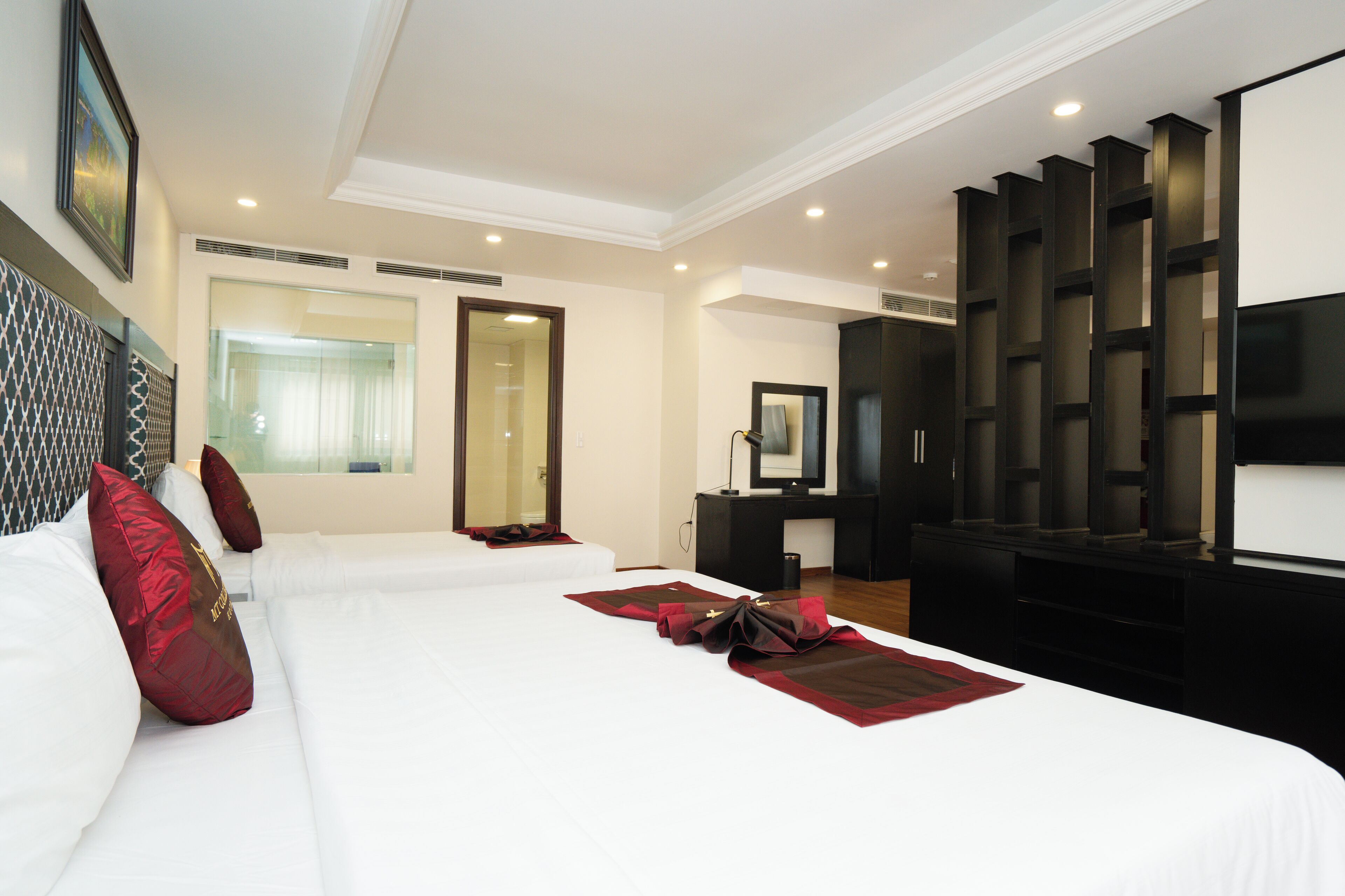 A hotel room with a large bed, a TV, a wardrobe, and a mirror.