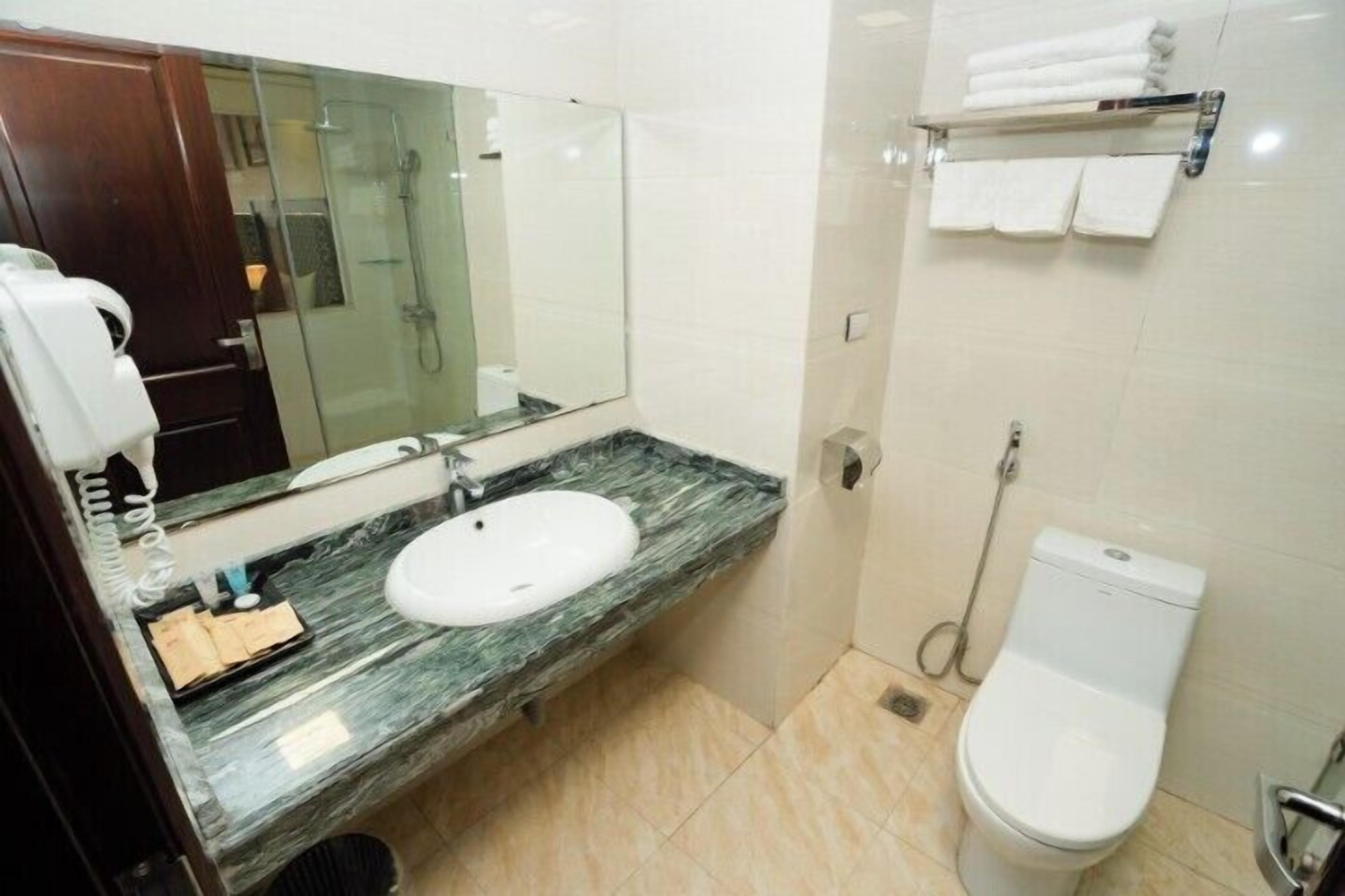 Een badkamer met een marmeren wastafel, toilet, douche en handdoekrek.