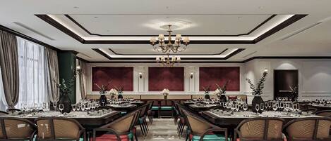 A formal dining room with multiple tables set for a meal, a chandelier, and a modern ceiling design.