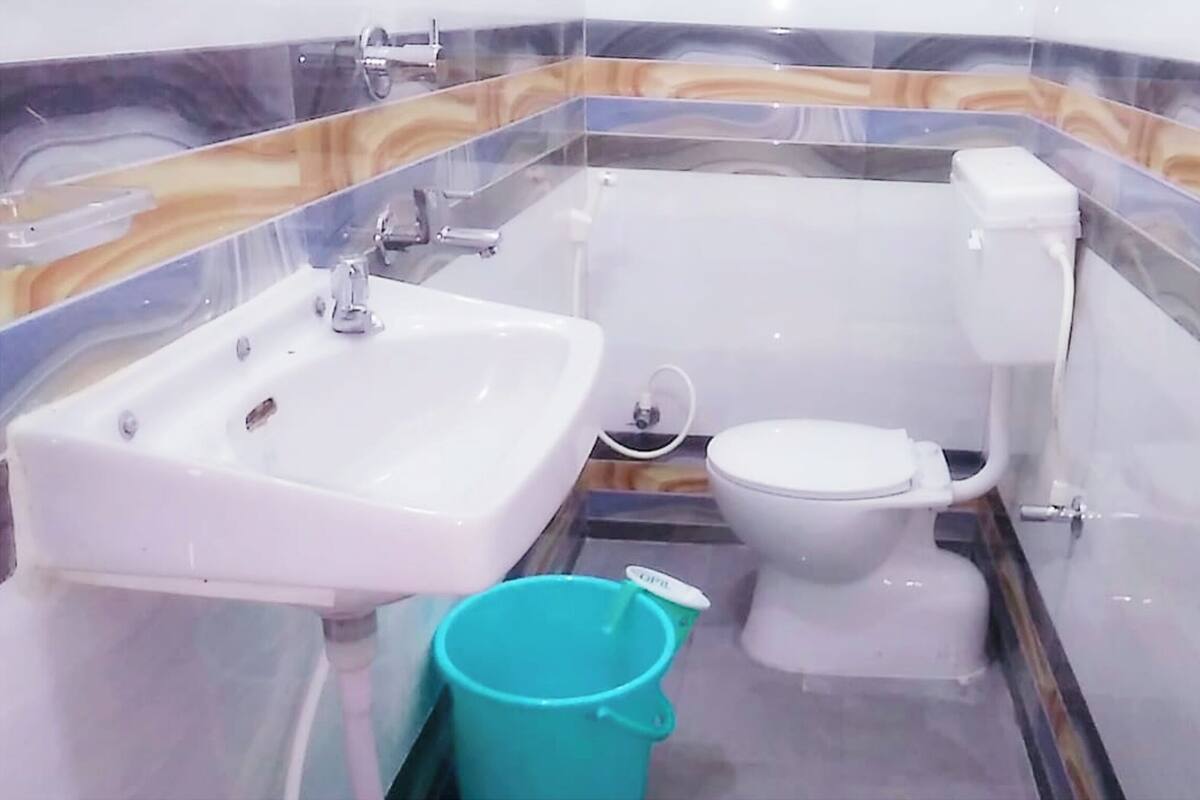 Ein kleines Badezimmer mit Waschbecken, Toilette und einem blauen Eimer.