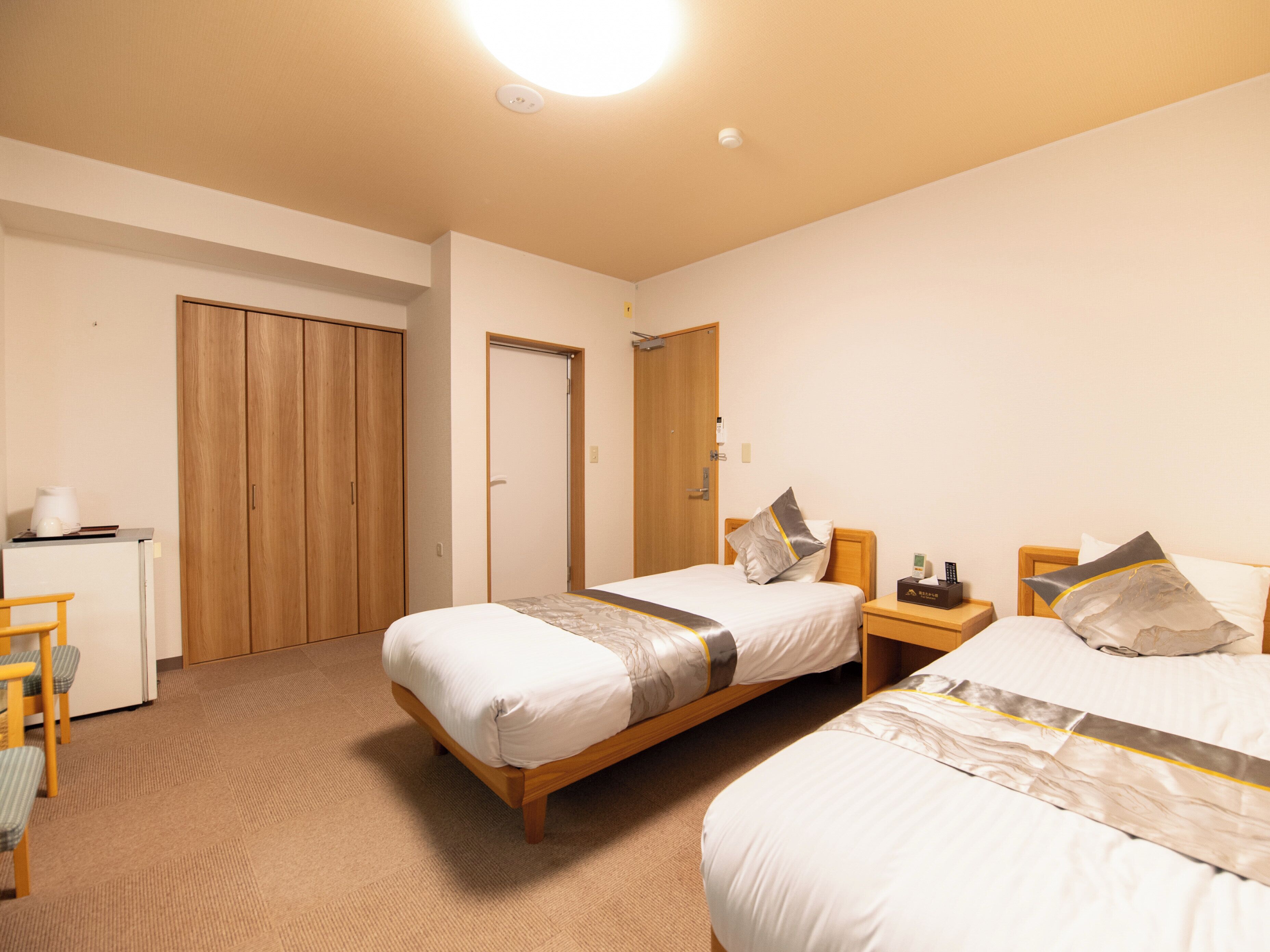 Quarto de hotel com duas camas, uma escrivaninha e um guarda-roupa.