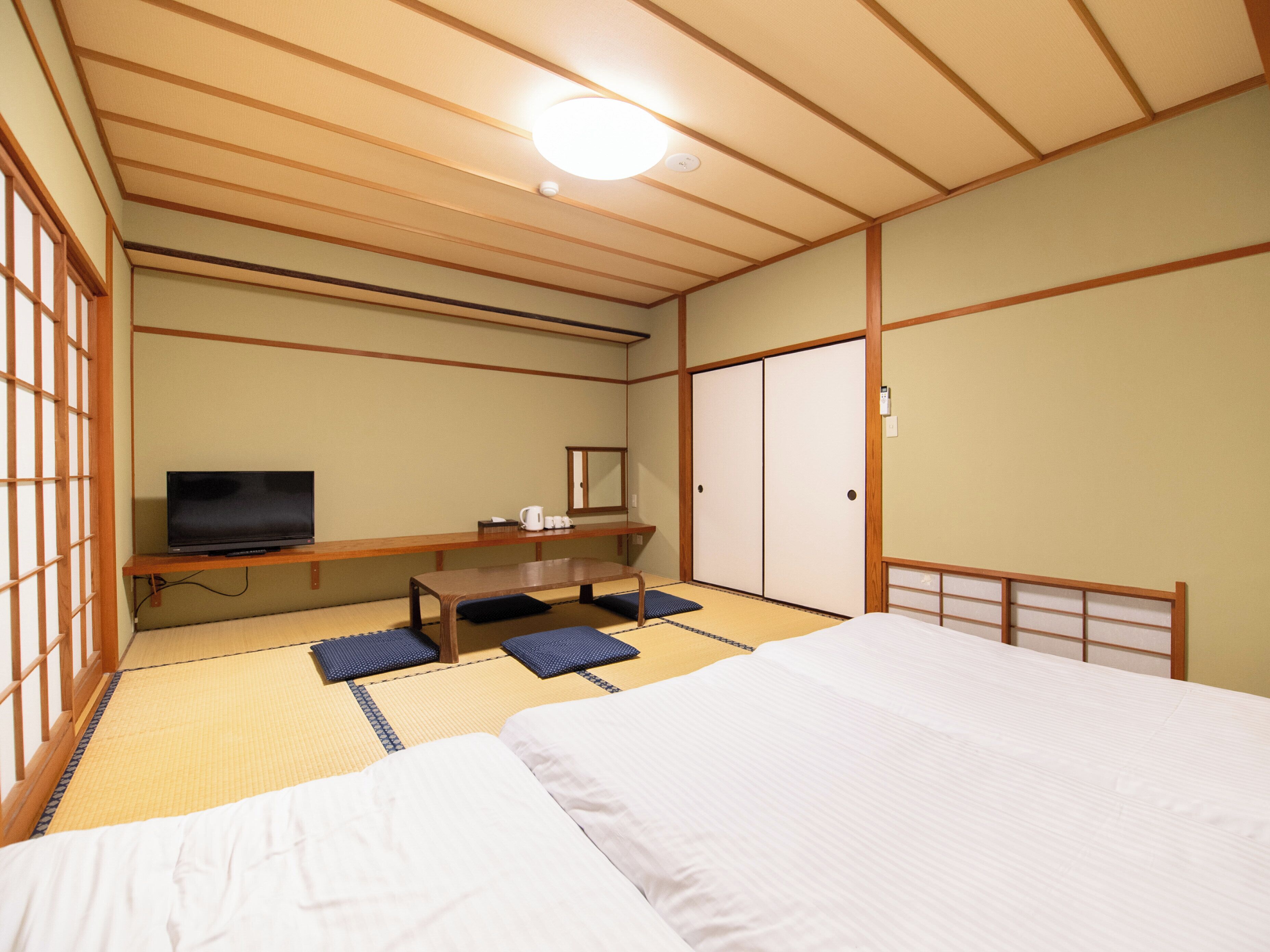 Una habitación de estilo japonés tradicional con suelo de tatami, televisor, escritorio y armario.