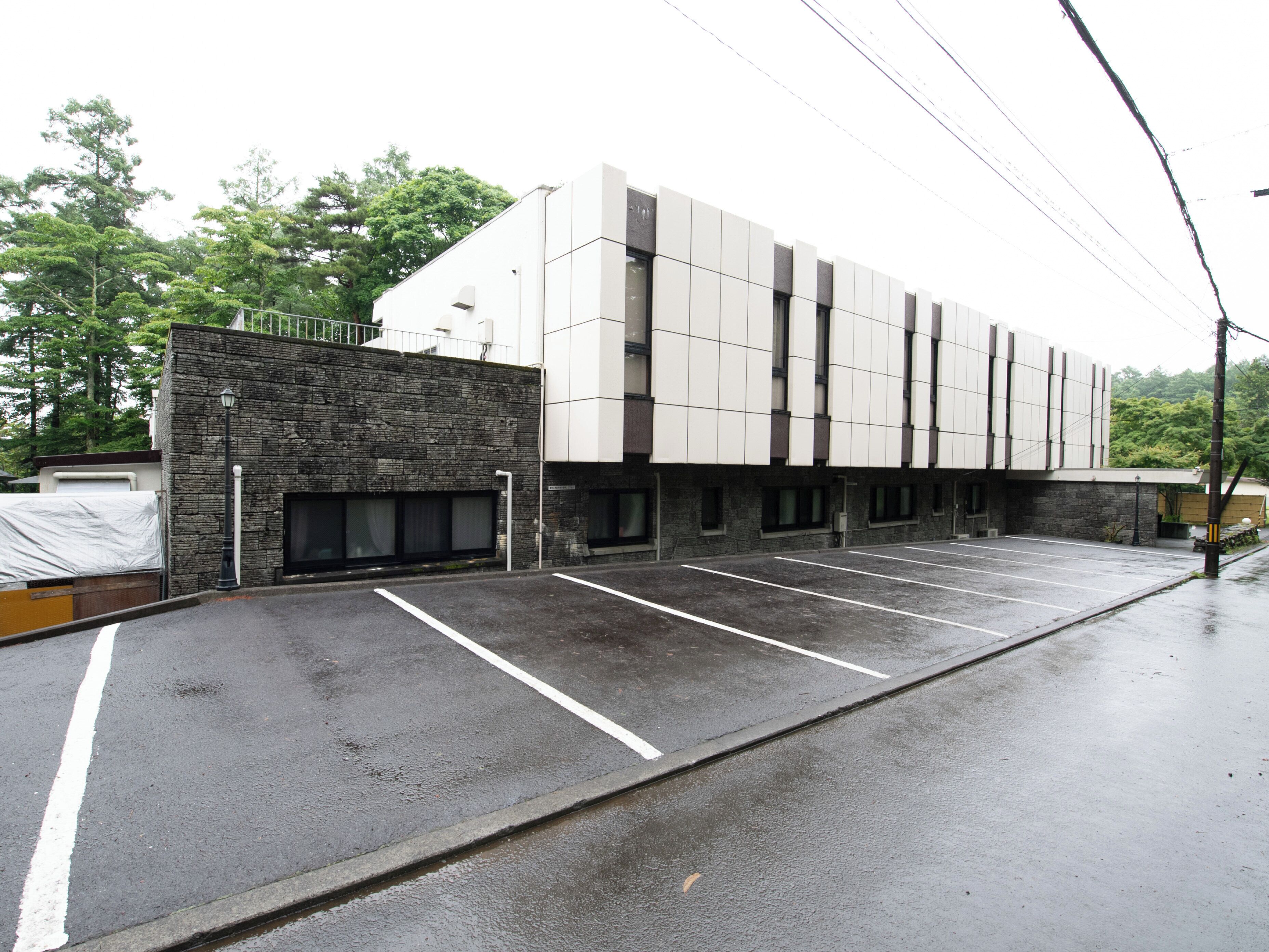 A modern building with a parking lot, stone facade, and multiple windows.