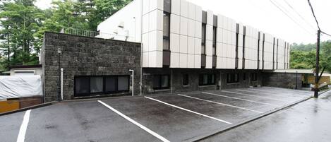 A modern building with a parking lot, stone facade, and multiple windows.