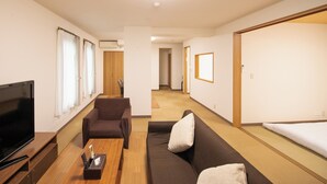Una sala de estar moderna con televisor de pantalla plana, un sofá, una silla y una mesa de centro de madera.