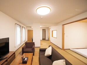 Una sala de estar moderna con televisor de pantalla plana, un sofá, una silla y una mesa de centro de madera.