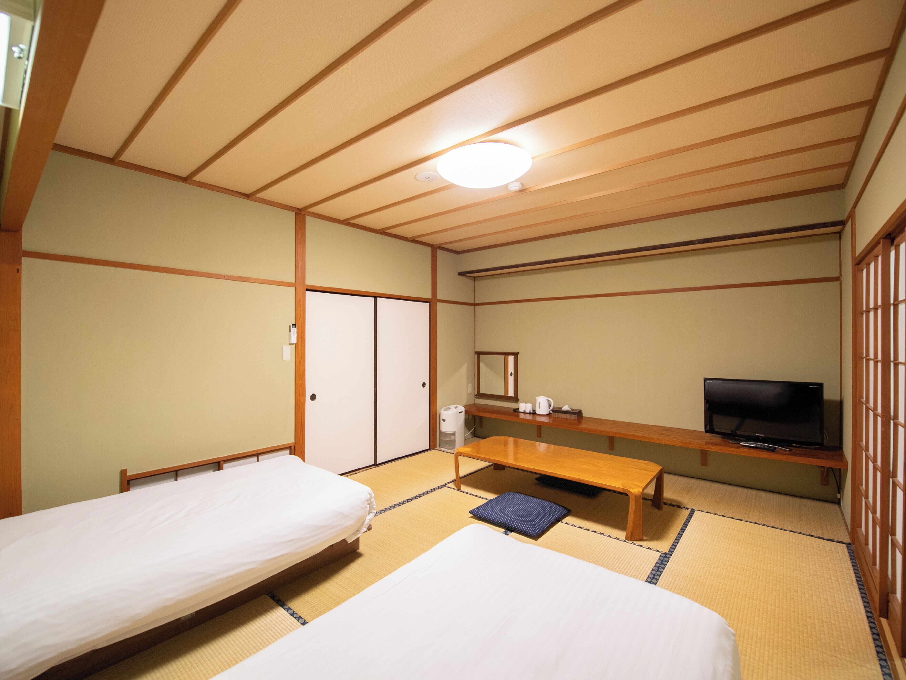 Een kamer met twee bedden, een televisie, een bureau en een spiegel.