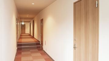 A hallway with carpeted floors, wooden doors, and recessed lighting.
