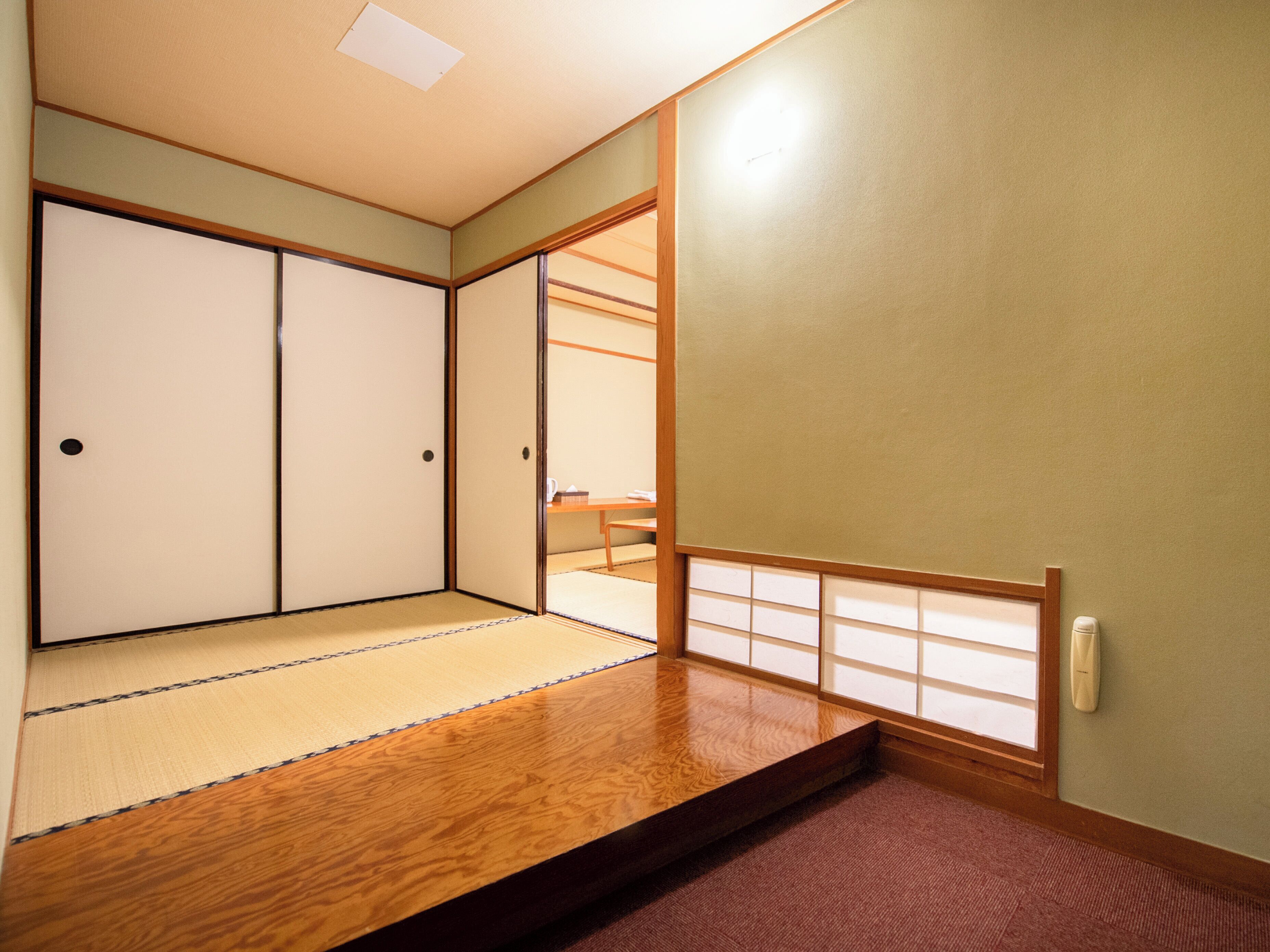 Een traditionele Japanse kamer met tatami vloerbedekking, schuifdeuren en een verlaagd houten platform.