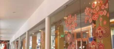 A corridor with seating areas and a storefront with festive decorations.