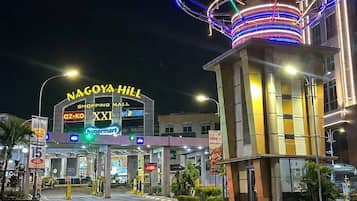 Entrada a un centro comercial con un letrero llamativo que dice 'NAGOYA HILL' y 'CENTRO COMERCIAL', con nombres de tiendas visibles como 'az-ko' y 'hypermart'.