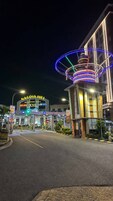 Entrada a un centro comercial con un letrero llamativo que dice 'NAGOYA HILL' y 'CENTRO COMERCIAL', con nombres de tiendas visibles como 'az-ko' y 'hypermart'.