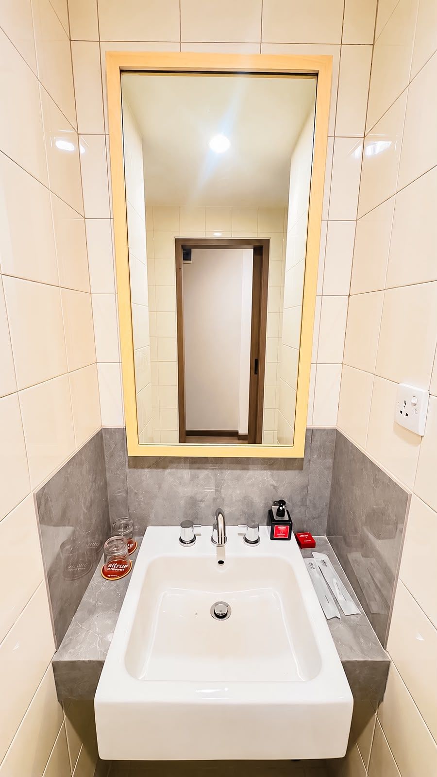 A bathroom with a white sink, a mirror with a wooden frame, and a towel dispenser.
