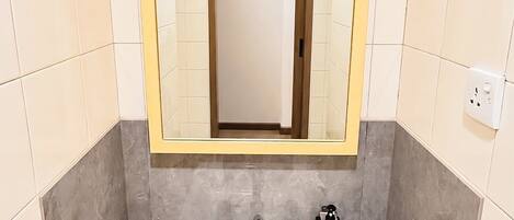 A bathroom with a white sink, a mirror with a wooden frame, and a towel dispenser.