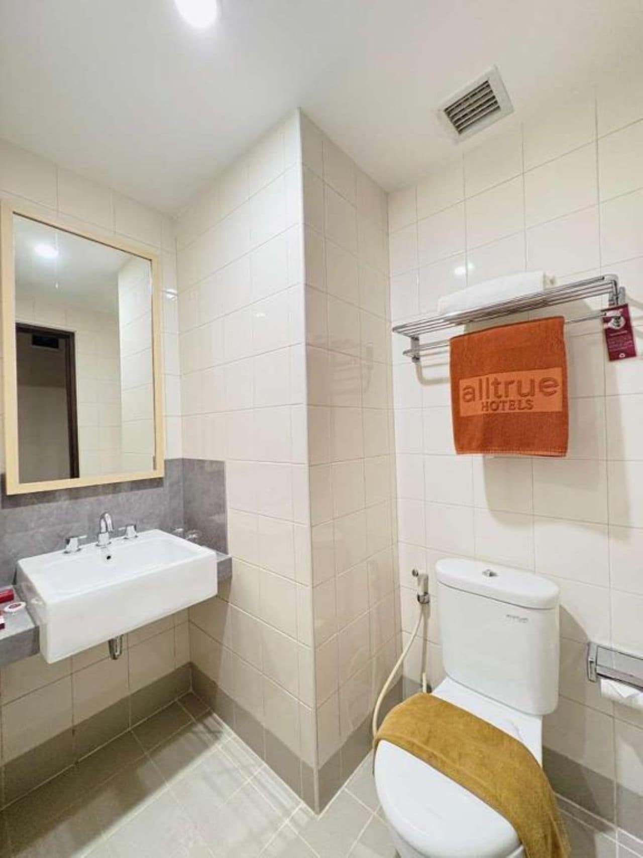 Ein Badezimmer mit weißem Waschbecken, einem Spiegel, einer Toilette und einem Handtuchhalter mit Handtuch.