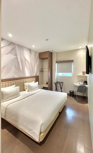 Une chambre d’hôtel moderne, dotée d’un grand lit, d’un bureau et d’une télévision.