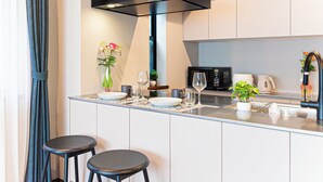 Una cocina moderna con una isla central, taburetes de bar, microondas y cafetera.