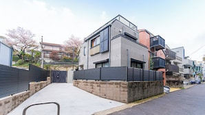 Un edificio residencial moderno con techo plano, ventanas amplias y entrada protegida por una reja.