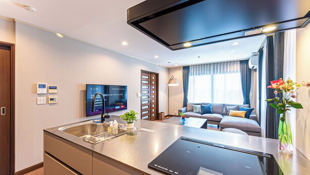 Una cocina moderna con estufa integrada, un lavamanos y un televisor de pantalla plana.