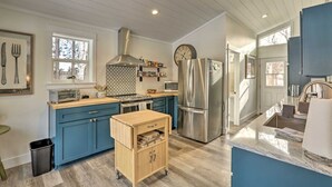 A modern kitchen with blue cabinets, a stainless steel refrigerator, and a wooden cart. - Cozy Farmhouse on 1 acre- Stargaze in the Hot tub (Bend)