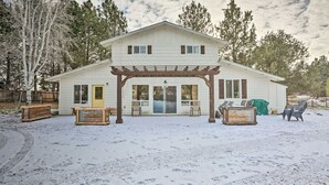 A two-story house with a covered patio area, a front door, and a small attached garage. - Cozy Farmhouse on 1 acre- Stargaze in the Hot tub (Bend)