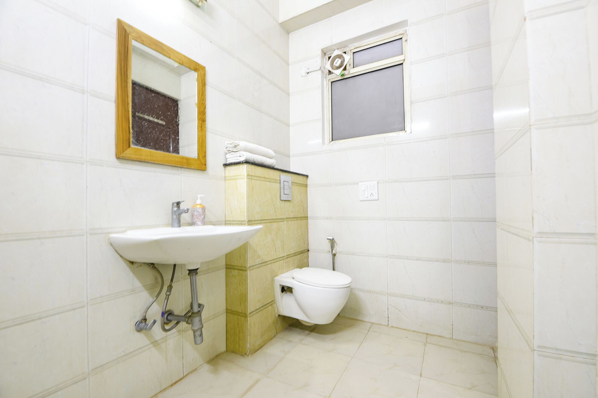 A small bathroom with a sink, toilet, and a mirror.