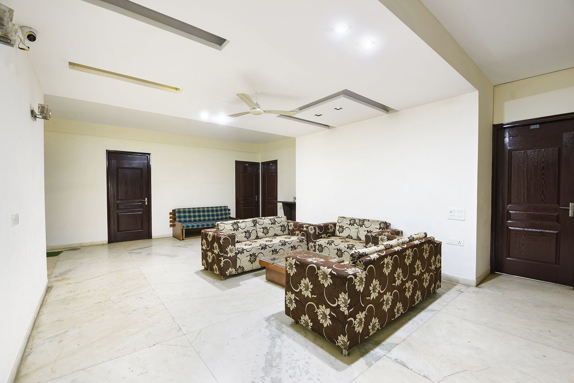 A spacious living room with a sectional sofa, a ceiling fan, and a large window.