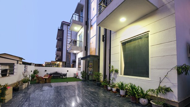 A modern building with a courtyard, potted plants, and outdoor furniture. - Gazelle By Wonderland (Gurugram)