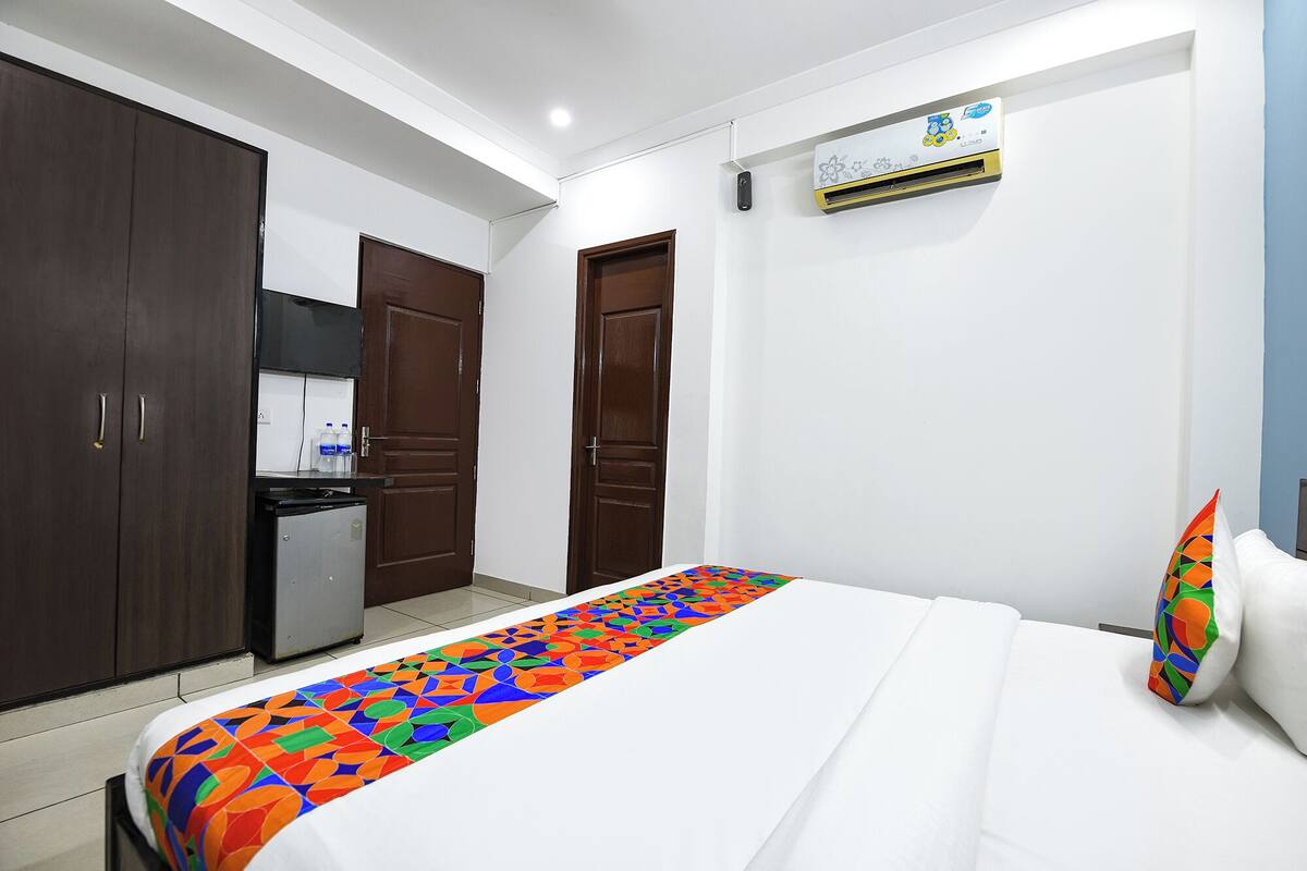 Een hotelkamer met een bed, een kledingkast, een kitchenette en een airconditioning.