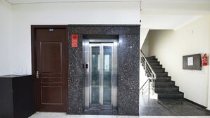 An elevator with a digital display, a staircase with a handrail, and a fire extinguisher on the wall. - Gazelle By Wonderland (Gurugram)