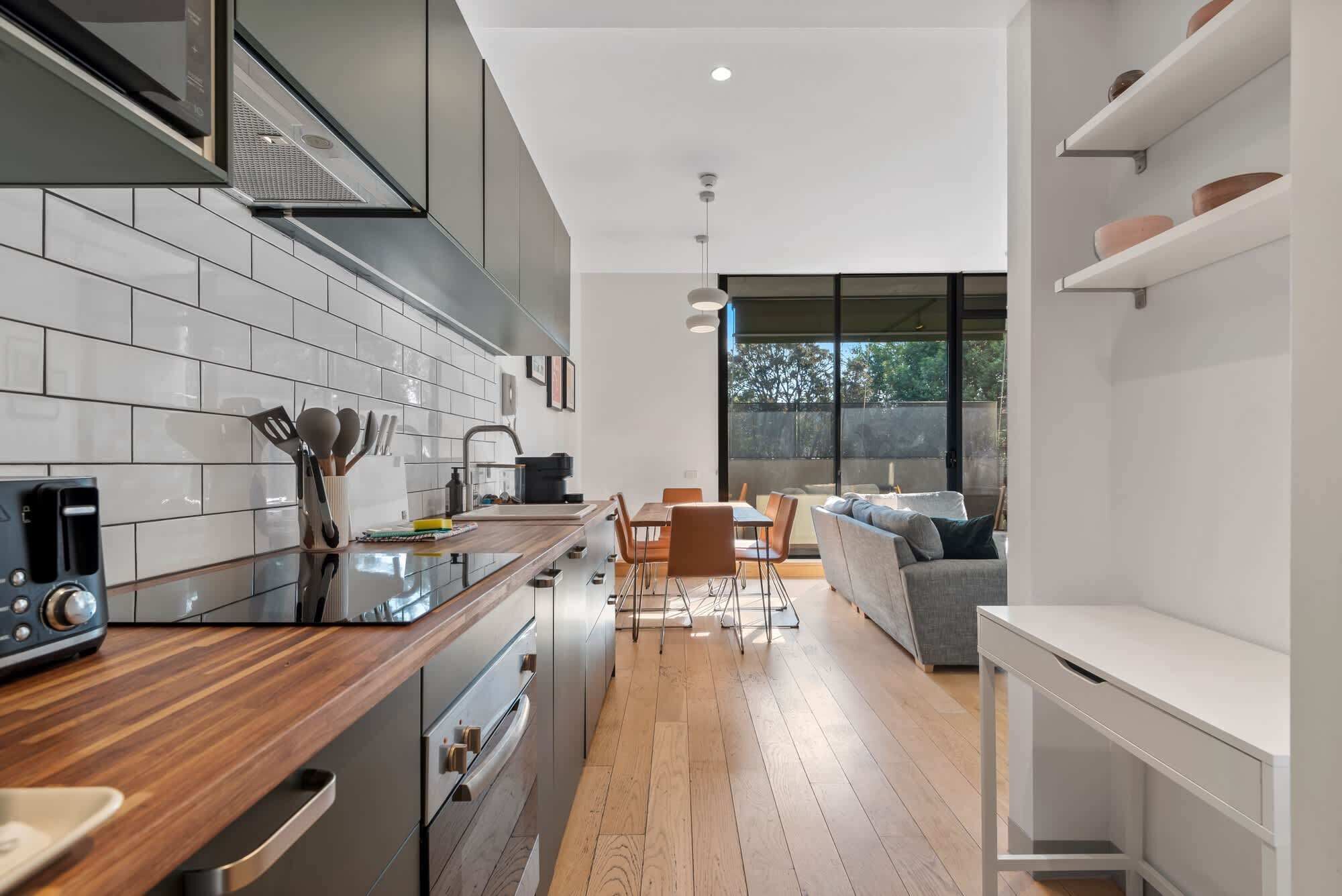 Una cocina moderna con encimera de madera, electrodomésticos de acero inoxidable y un comedor con sofá y sillas.