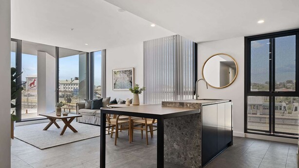 A modern kitchen with a central island, large windows, and a view of the city.