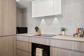 A modern kitchen with wooden cabinets, a black countertop, and a built-in oven.