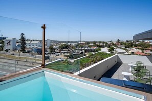A rooftop pool with a clear view of a town and a building with a kangaroo logo. - Trendy 1-Bed Retreat in Fremantle with Rooftop (North Fremantle)