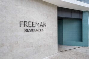 Een moderne entree van een gebouw, met de naam "FREEMAN RESIDENCES" op een lichtgekleurde muur.